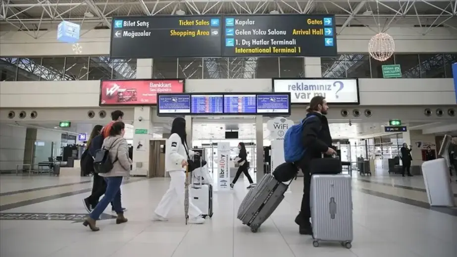 Antalya Havalimanı terminalinde uçuş bilgi ekranı ve yolcular