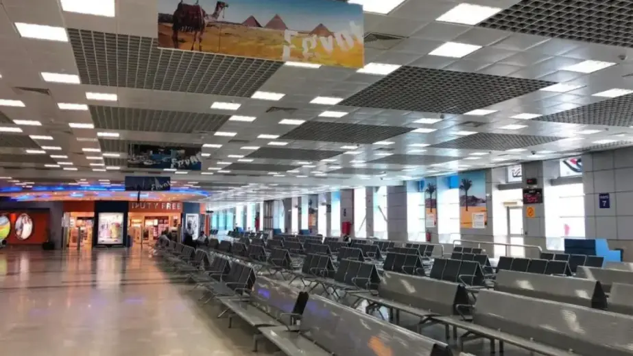 Innenbereich des Terminalgebäudes mit Duty-free-Bereich, Sitzbänken, Wartehalle und Egypt-Plakat mit