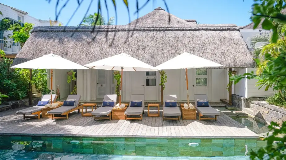 Woman swimming in the pool at La Maison 20 Degrés Sud with palm trees, cabana and table
