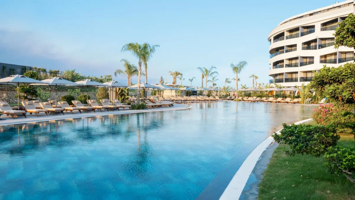 Swimmingpool, Palmen, Hotelgebäude und Grünanlagen im Liu Resorts Hotel.