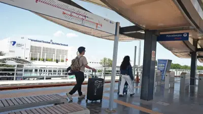 Fahrgäste an der Antray-Haltestelle am Flughafen Antalya mit Terminal 1 im Hintergrund