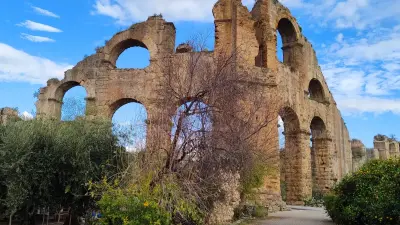 Ancient Roman aqueducts of Aspendos with trees and cloudy sky