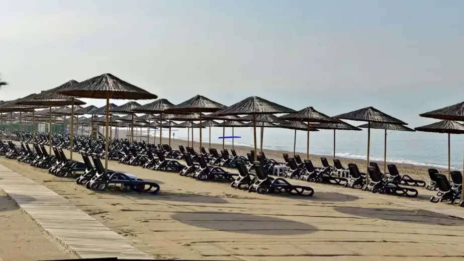 Strand des Lago Hotels mit Liegen, Sonnenschirmen, Küste und einem Boot im Meer