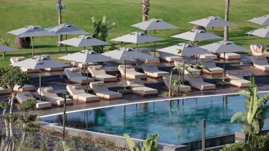 Sonnenliegen und Sonnenschirme am Pool, umgeben von Rasenflächen und Grünanlagen im Liu Resorts Hote