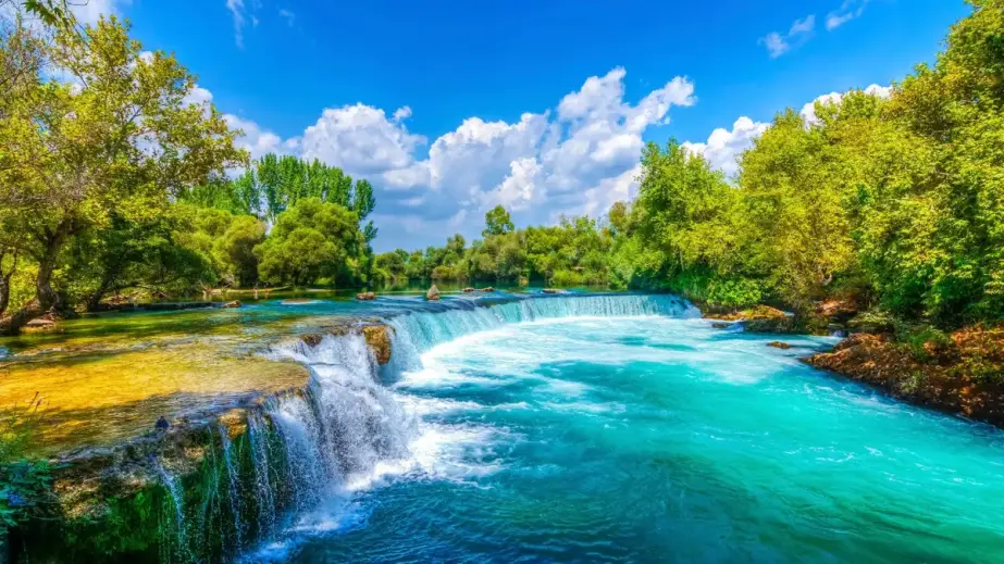 Der von Bäumen gesäumte Manavgat-Wasserfall und der Fluss Manavgat unter Wolken